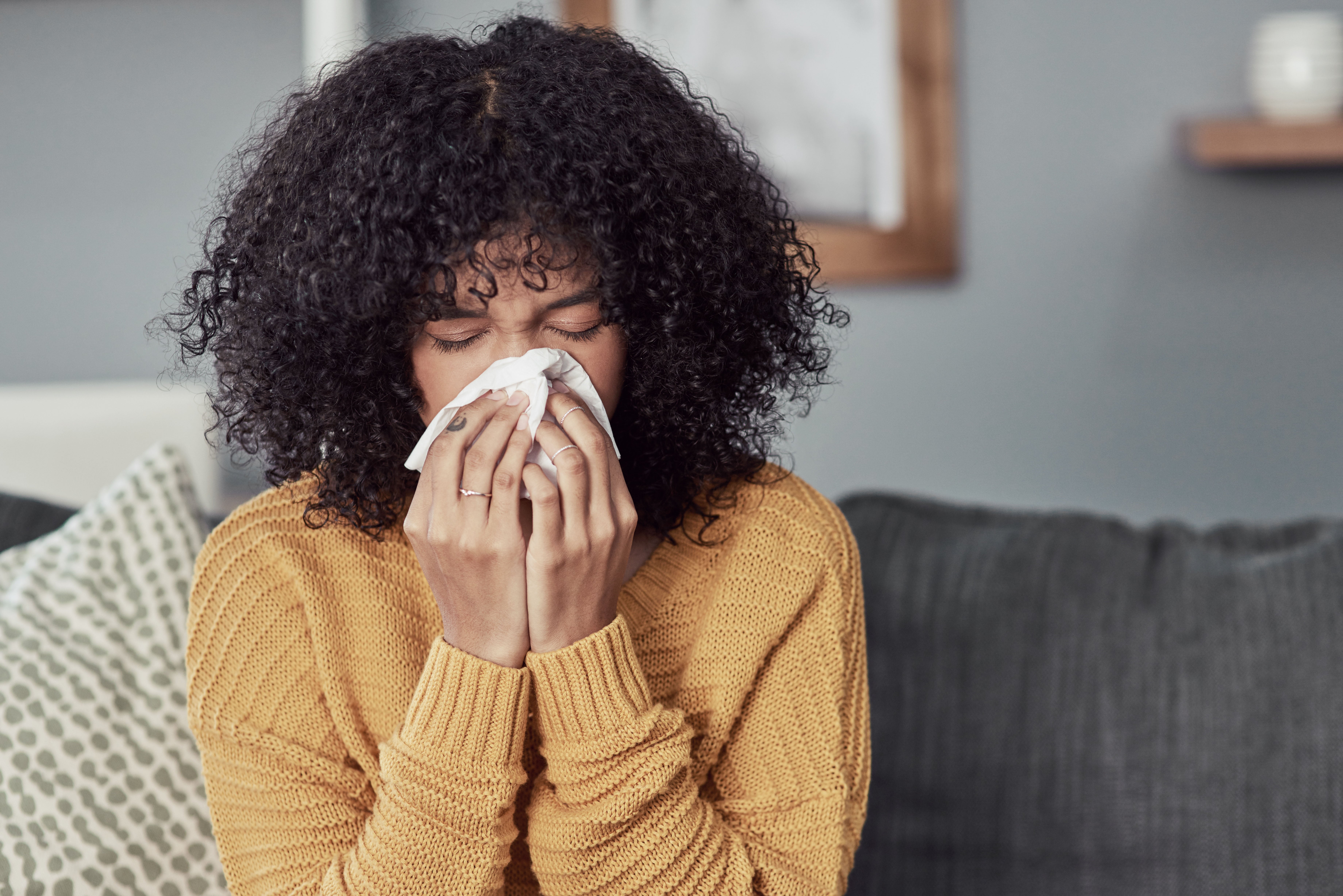 Woman blowing her nose at home