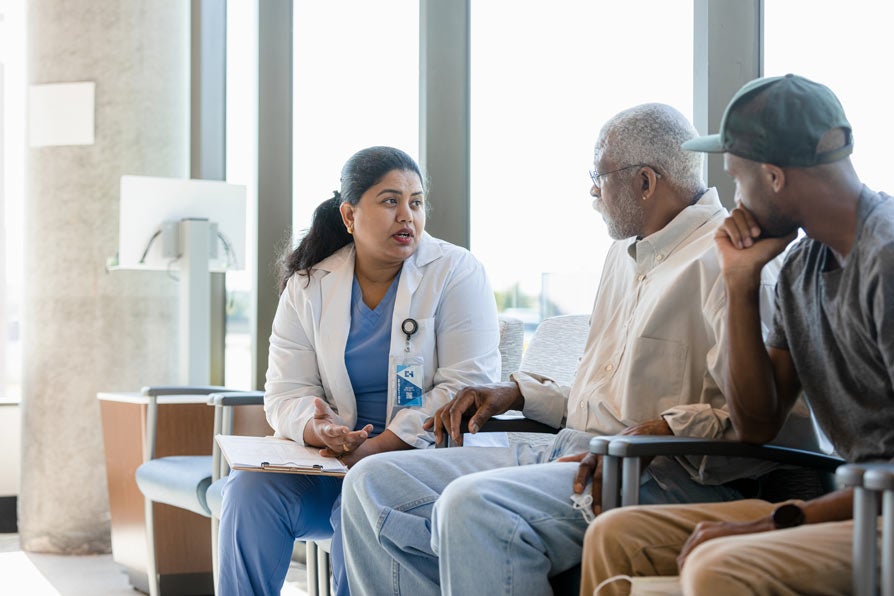 Senior man and son listen to female doctor